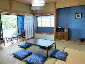 a room with a table and blue walls and windows at I Love Izu in Futo