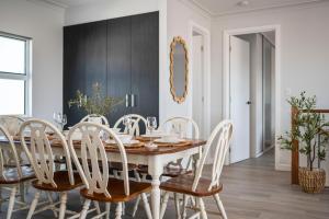 a dining room with a wooden table and white chairs at C-Views - Aldinga Beach - C21 SouthCoast Holidays in Aldinga Beach +33 photos