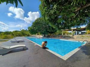 a man is sitting next to a swimming pool at LOHAS Airport Hotel and Restaurant in Cagayan de Oro