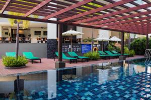ein Hotelpool mit grünen Liegestühlen und Sonnenschirmen in der Unterkunft Andakira Hotel - SHA Extra Plus in Patong Beach