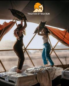 two girls are standing on a bed with umbrellas at Traditions of Wadi Rum camp & jeep tour in Wadi Rum