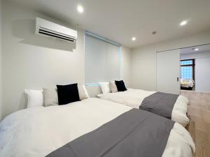 two beds in a room with white walls at Hiroshima Hotel in Hiroshima