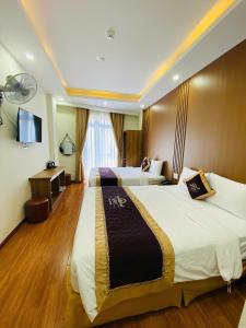 a hotel room with two beds and a television at Queen Villa 3 Hotel DL - by BAY LUXURY in Da Lat