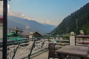 a balcony with a table and a view of a valley at Ride At Hill-Nihal Hotel & Cottage in Manāli