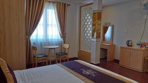 a hotel room with a bed and a table and chairs at Queen Villa Hotel 2 DL - by BAY LUXURY in Da Thien +3 photos