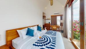 a bedroom with a bed with blue and white pillows at Segara Seaside Resort in Nusa Lembongan