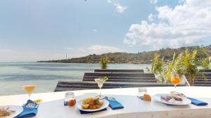 a table with food and drinks and the ocean at Segara Seaside Resort in Nusa Lembongan