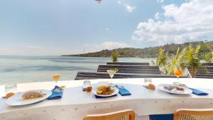a table with plates of food and the ocean at Segara Seaside Resort in Nusa Lembongan