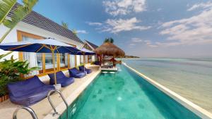 a pool with chairs and umbrellas next to the ocean at Segara Seaside Resort in Nusa Lembongan