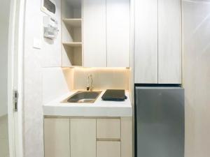 Una pequeña cocina con fregadero y refrigerador. en Elegant and Homey Studio at Amartha View Apartment By Travelio, en Semarang