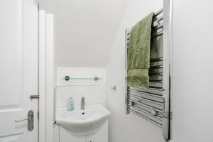 a white bathroom with a sink and a mirror at Swiss Haven - Spacious 3 Bedroom House in Liverpool +41 photos