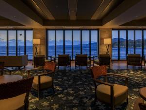 a hotel lobby with tables and chairs and a view of the water at Inatori Ginsuiso in Higashiizu