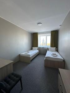 a room with two beds and a chair and a window at Гостиница Kokshe Inn in Kokshetau