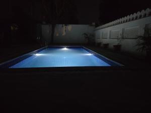 a swimming pool at night with lights in the dark at Yellow Bells in Udaipur