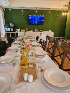 a long table with white plates and flowers on it at Dworek Szumilas in Prudnik