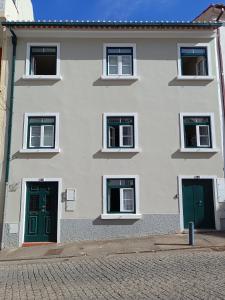 un edificio bianco con porte verdi su una strada di Bragança Apartamento Studio a Bragança