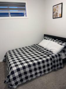 a bed with a black and white checkered blanket at Exquisite Basement Suite, 7mins away to Landmark Cinema and Malls in Calgary