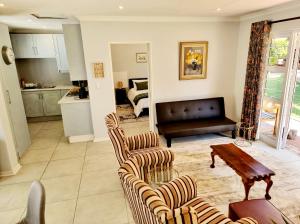 ein Wohnzimmer mit Sofa, Stühlen und einem Tisch in der Unterkunft Coconut Cottage in Randburg