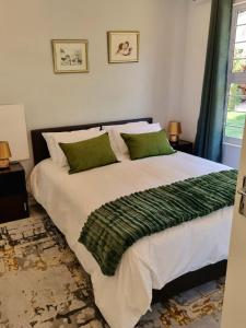 ein Schlafzimmer mit einem großen Bett mit grünen Kissen in der Unterkunft Coconut Cottage in Randburg