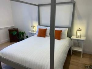 Peaceful apartment with courtyard in town centre في تيتبري: غرفة نوم بسرير وملاءات بيضاء ومخدات برتقالية