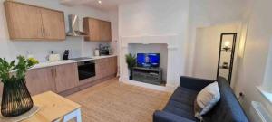 Peaceful apartment with courtyard in town centre في تيتبري: غرفة معيشة مع أريكة زرقاء ومطبخ