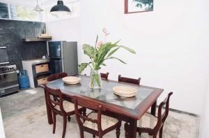 a dining room table with chairs and a vase of flowers at Coastal Cloud Backpackers in Unawatuna
