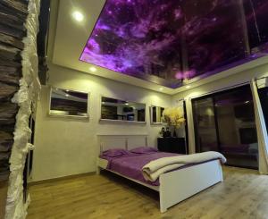 a bedroom with a bed with a purple ceiling at Stone Spa Apartman 2 in Sremčica