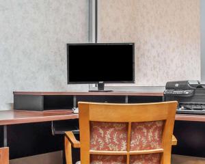 a computer monitor sitting on a desk with a chair at Econo Lodge Elmira-Corning in Elmira