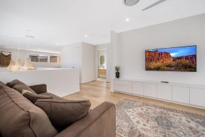 a living room with a couch and a tv on a wall at 47 Theresa Street Golden Beach in Golden Beach