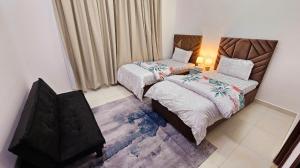 迪拜Elegant Villa Rooms in Dubai near Airport的一间卧室，有两张床和一张带灯的桌子