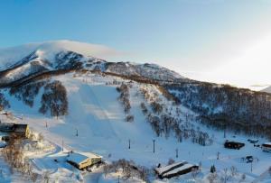 a snow covered mountain with a ski lodge on it at Pension Cotton Farm in Niseko