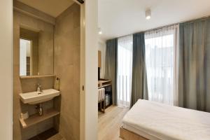 bagno con lavandino, letto e finestra di Hôtel Rousseau Plus a Ginevra