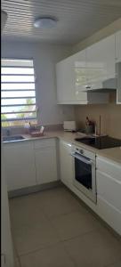 a kitchen with white cabinets and a sink and a stove at L'appartement de la plage in Le Diamant