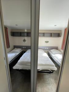 a room with three beds and a mirror at Mobil home Le Riesling 6 personnes climatisé in Boofzheim +3 photos