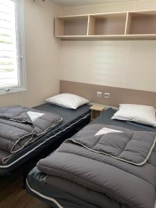 two beds sitting next to each other in a room at Le Riesling - Mobilhome pour 6 - TV - Climatisé in Boofzheim