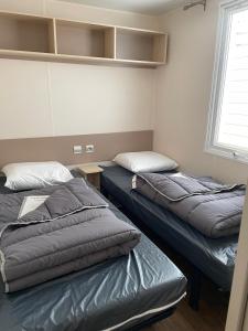 a room with two beds and a window at Le Riesling - Mobilhome pour 6 - TV - Climatisé in Boofzheim