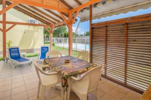 a dining room with a table and chairs on a patio at Villa Cannelle - Maison climatisée St-François in Saint-François
