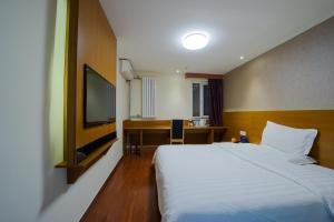 a hotel room with a bed and a flat screen tv at 7Days Premium Harbin Heping Road Provincial Government in Harbin