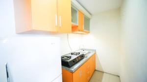 a small kitchen with a stove and cabinets at Strategic Studio Apartment at High Point Serviced By Travelio in Siwalapkerto
