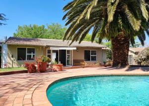 ein Haus mit einer Palme und einem Pool in der Unterkunft Coconut Cottage in Randburg