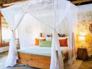 a bedroom with a bed with a mosquito net at Villa Juliana in Jambiani