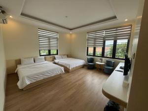 a bedroom with two beds and a desk and two windows at Happy Home Dak Lak in Buôn Mhang