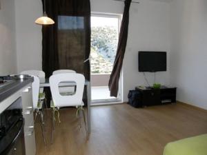 a living room with a table and chairs and a television at Apartments Rusulica in Vinišće