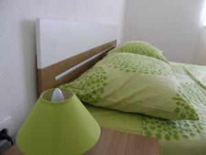 a green bed with two pillows and a lamp at Apartments Rusulica in Vinišće