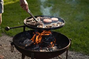 a person is cooking food on a grill at Grassington Farm by Wigwam Holidays in Helston