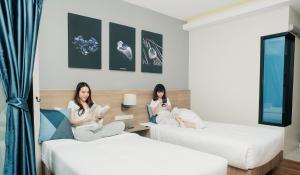 twee vrouwen op bedden in een hotelkamer bij Blue Rabbit Hotel in Chanthaburi