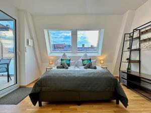 a bedroom with a large bed with two windows at Auszeit Apartment LAKELIFE in Friedrichshafen