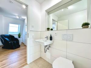 a white bathroom with a sink and a mirror at Auszeit Apartment LAKELIFE in Friedrichshafen +34 photos