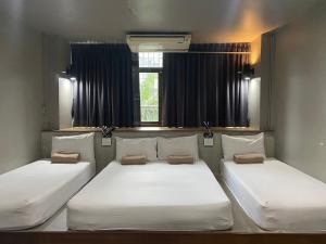 two beds in a room with two windows at Yaksa Private in Bangkok