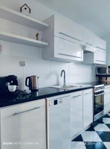 Una cocina con gabinetes blancos y una encimera negra. en Apartament na poddaszu M.CH. - Ustka, en Ustka